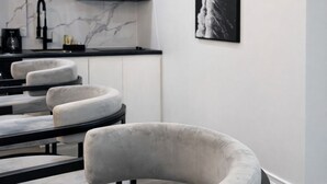 Eine moderne Küche mit weißen Schränken, einer schwarzen Arbeitsplatte und einem schwarz-weißen abstrakten Gemälde an der Wand.