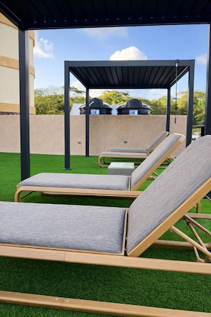 Un espacio de estar al aire libre con sillones de relax y césped artificial.