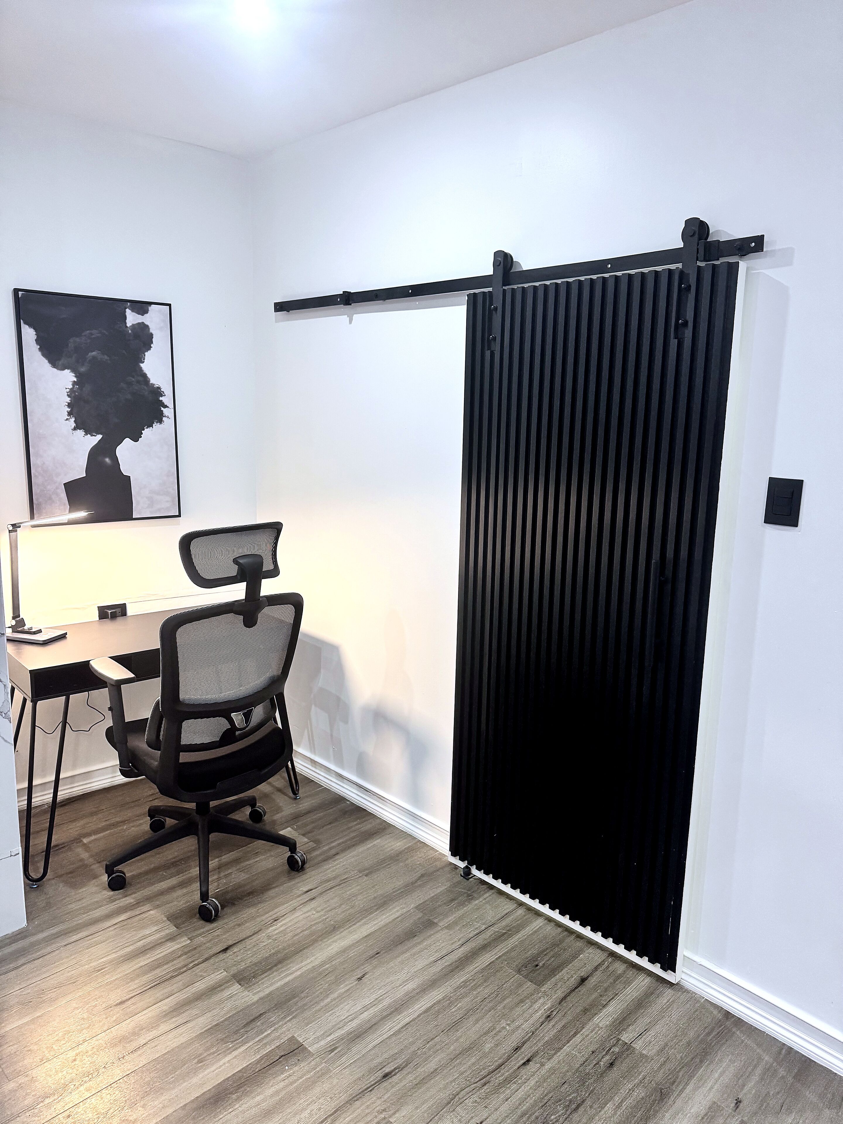 A modern office space with a desk, office chair, and a sliding door.