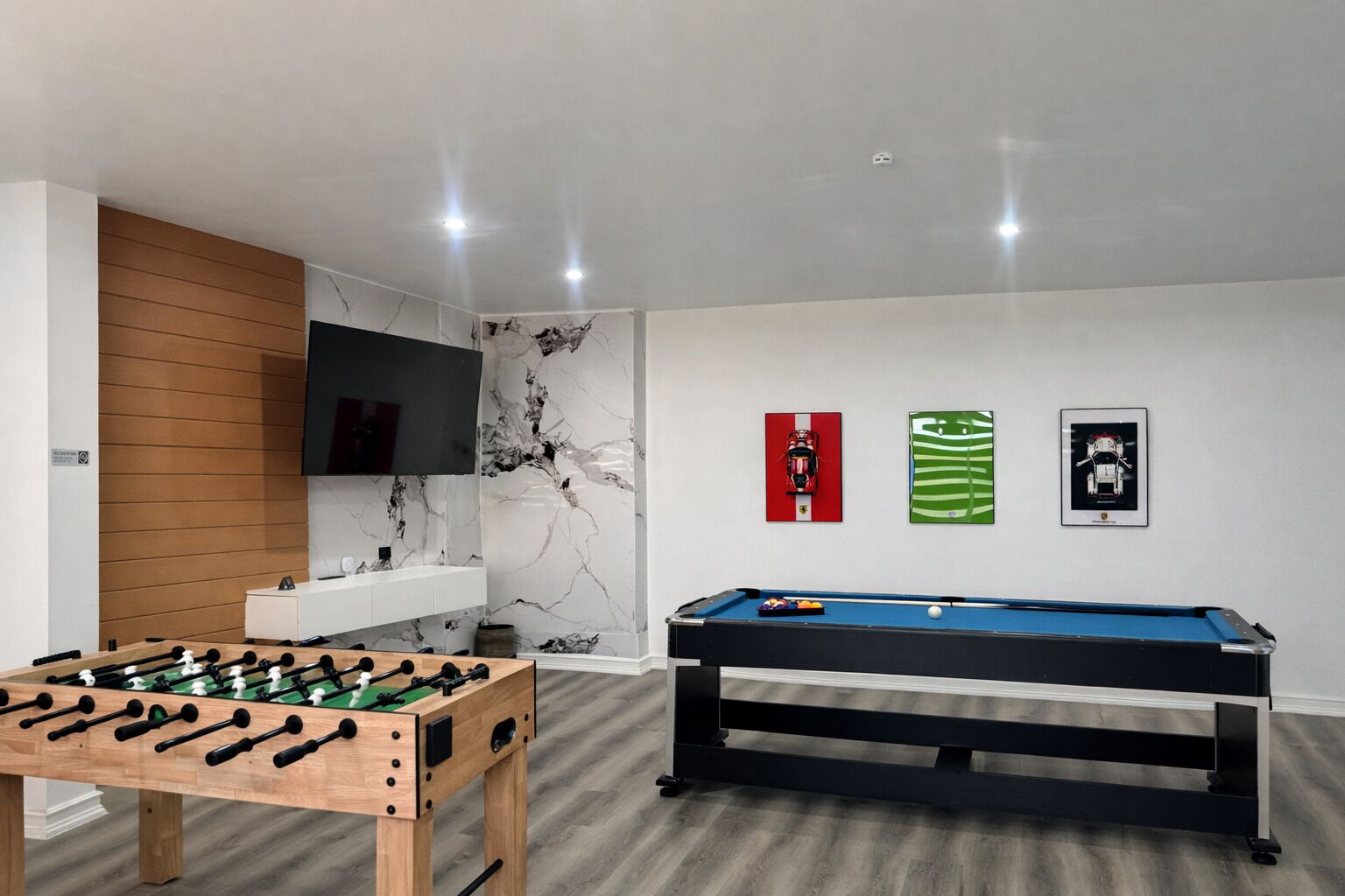 Une pièce équipée d’un baby-foot, d’une table de billard, d’un téléviseur fixé au mur et agrémentée d’œuvres d’art mural.