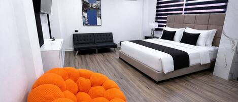 Quarto moderno com cama, sofá, poltrona de saco e um quadro na parede.
