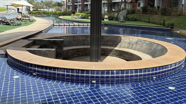 A swimming pool with a tiled deck, a central water feature, and a covered seating area. - Charming 1-bedroom Apartment Near Bangrak Beach (Koh Samui)