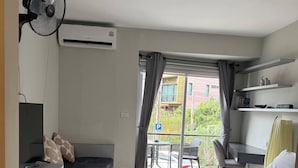 A modern bedroom with a bed, a desk, a chair, and a balcony with a view of the outside. - Charming 1-bedroom Apartment Near Bangrak Beach (Koh Samui)