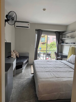 A modern bedroom with a bed, a desk, a chair, and a balcony with a view of the outside. - Charming 1-bedroom Apartment Near Bangrak Beach (Koh Samui)