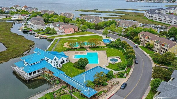 Ett stort hus med ett blått tak, en swimmingpool och en brygga som sträcker sig ut i en sjö.
