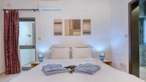 Une chambre d’hôtel comprenant un lit, deux lampes de chevet, un miroir et un espace douche.