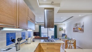 Une cuisine moderne avec des meubles en bois, une hotte de cuisinière en acier inoxydable, un grille-pain encastré et un coin repas avec une table et des chaises.