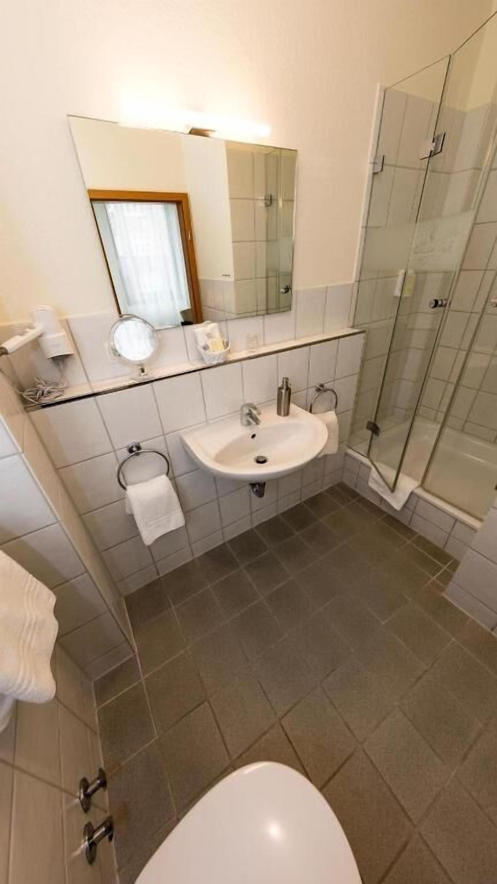 Ein Badezimmer mit Waschbecken, Duschkabine aus Glas und Toilette.