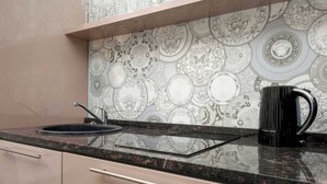 A kitchen with a patterned backsplash, a black coffee maker, and a modern faucet. - Functional Studio in the Heart of Poznań | 3 min to Market Square (Poznań)