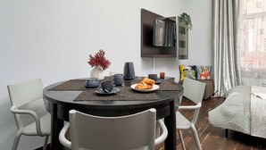 A modern dining area with a round table, chairs, and a TV mounted on the wall. - Functional Studio in the Heart of Poznań | 3 min to Market Square (Poznań)
