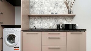 A compact kitchen with a washing machine, a microwave, and a decorative backsplash. - Functional Studio in the Heart of Poznań | 3 min to Market Square (Poznań)