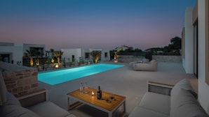 A modern outdoor pool area with a wooden table, seating, and a stone wall. - The Palms Resort 2BR Villa Dream Five with Pool (Tkon)