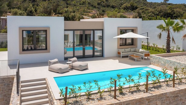 A modern outdoor pool area with a clear blue pool, white outdoor furniture, and a view of a hillside with trees. - The Palms Resort 2BR Villa Dream Five with Pool (Tkon)