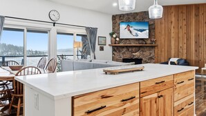 A modern kitchen with a large island, wooden cabinets, and a stone accent wall. - Buffalo Mtn Views - Spacious Dillon Retreat (Dillon)