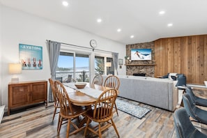 Una sala de estar moderna con comedor, chimenea y vistas al exterior.