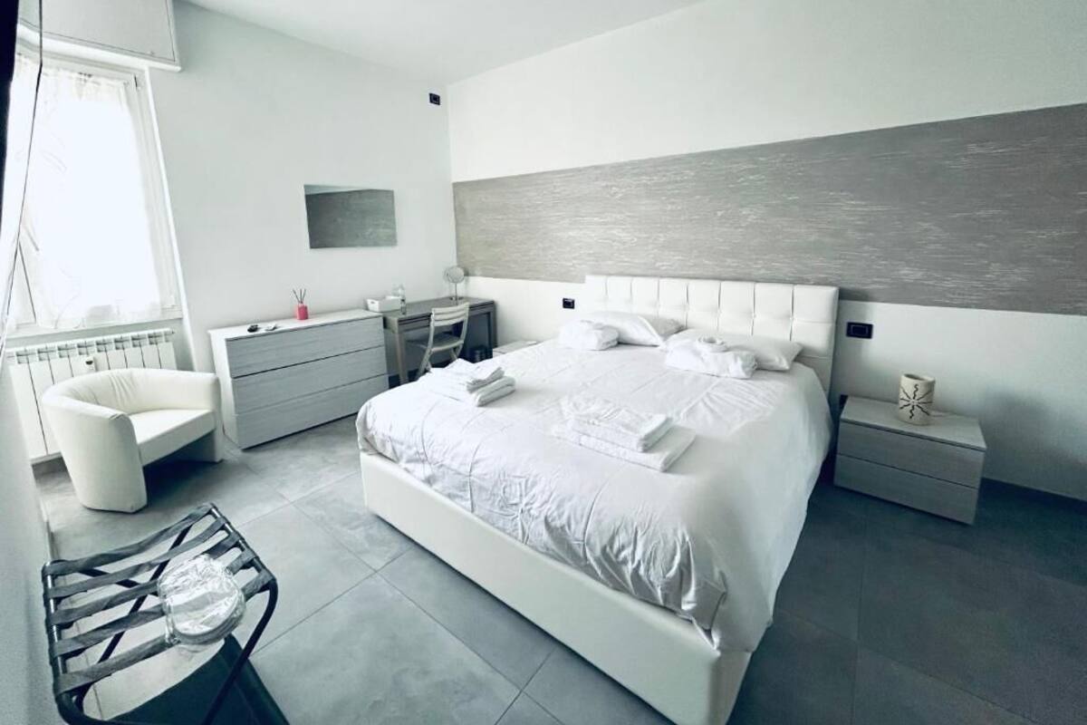 Une chambre moderne avec un grand lit, des tables de chevet, une chaise et un radiateur.