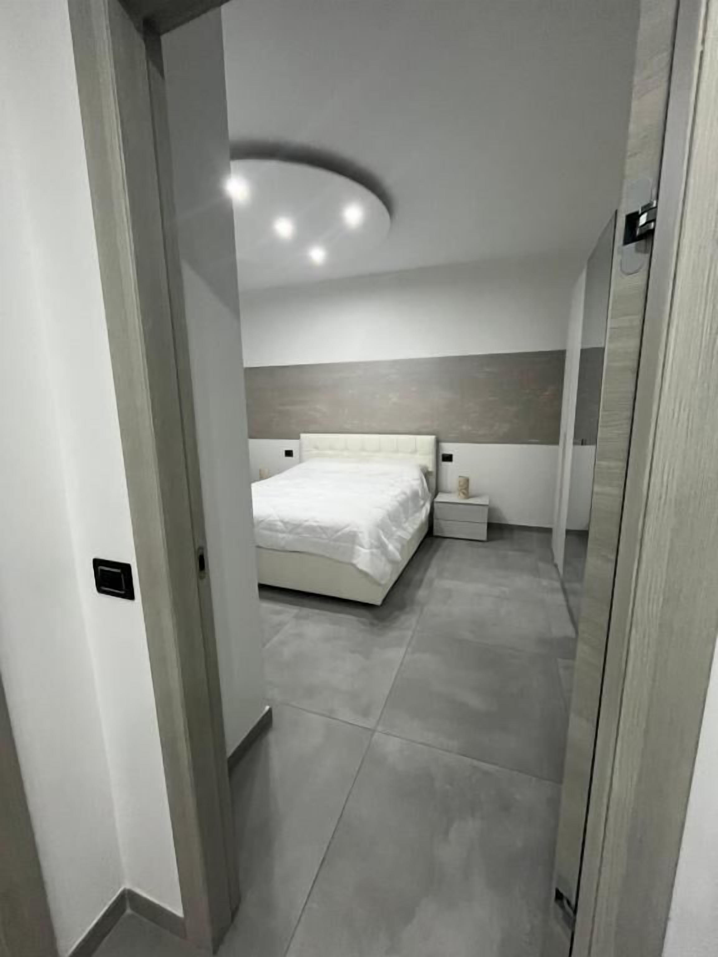 A modern bedroom with a large bed, bedside tables, and a neutral color scheme.
