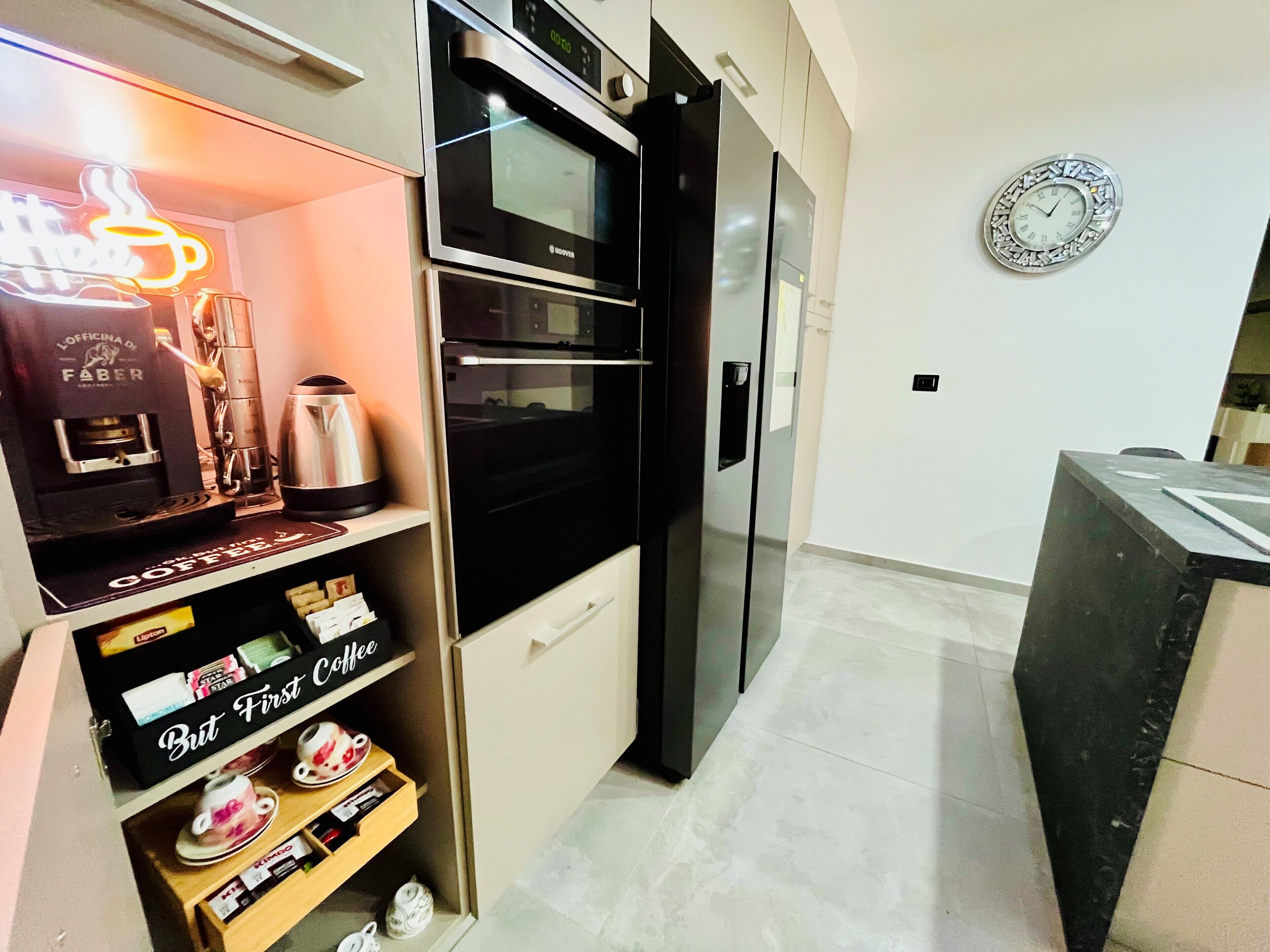 A modern kitchen with a coffee machine, a clock, and a coffee display.