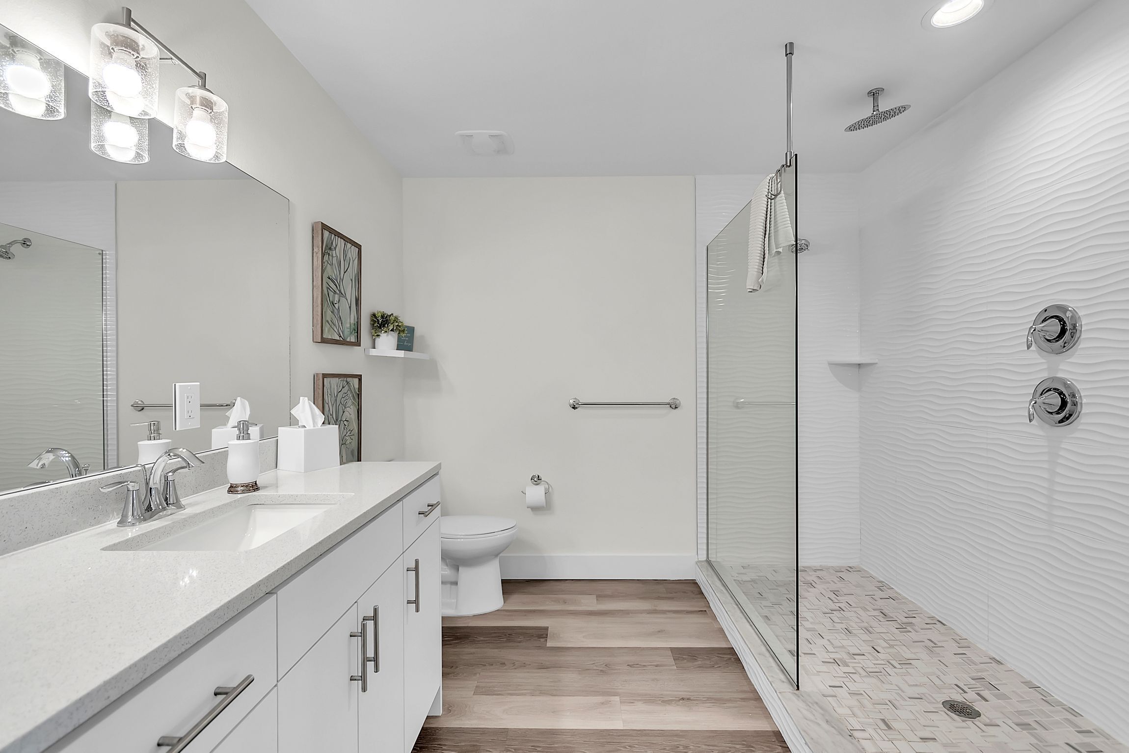 A modern bathroom with a large mirror, a shower, and a toilet.