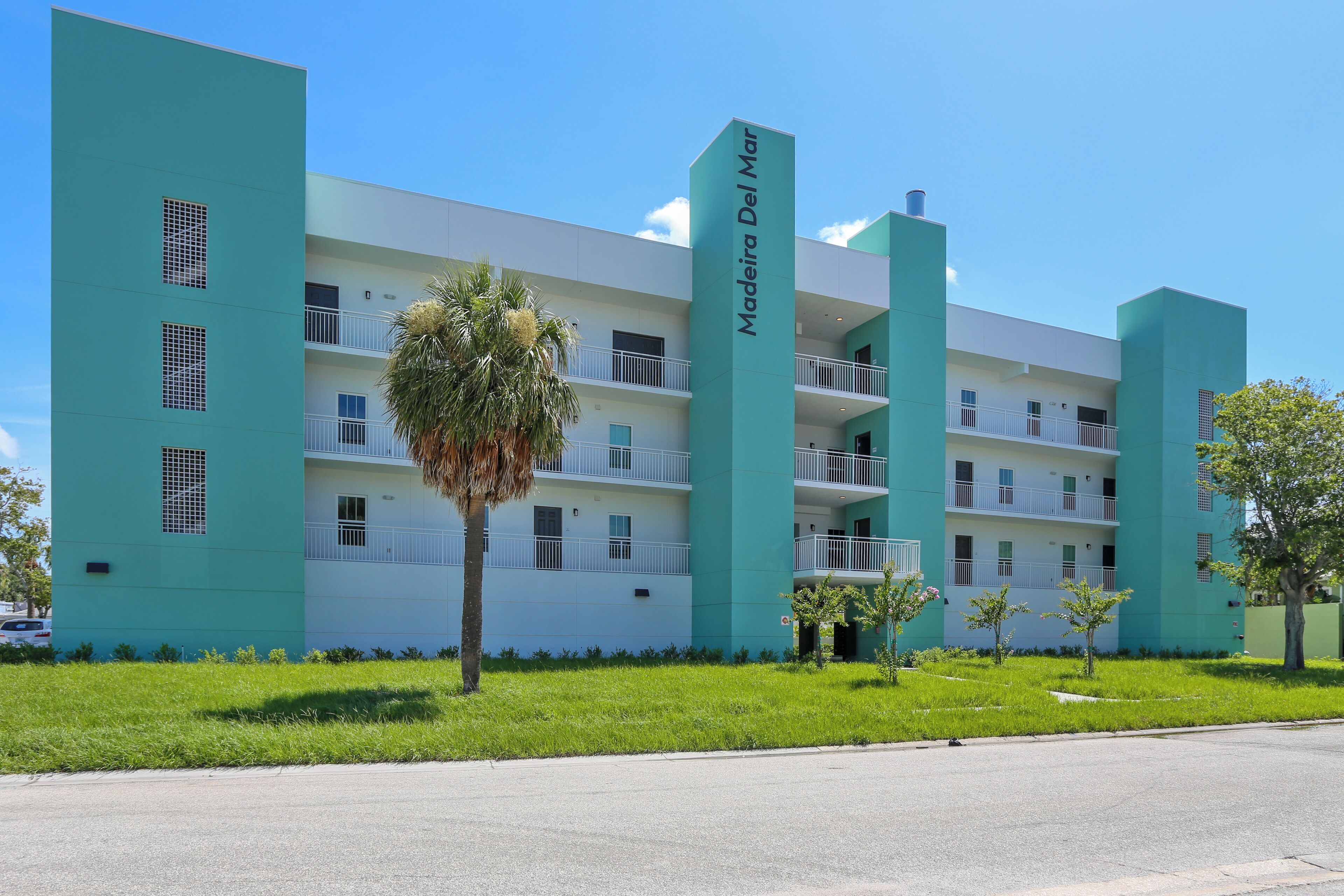 A multi-story hotel with a modern design, featuring balconies on each floor and a prominent name sign.