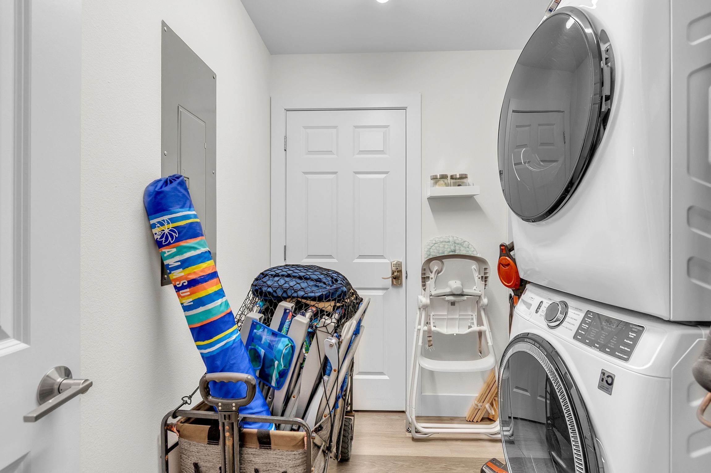 A laundry area with a washing machine, a drying rack, and a cart with laundry items.