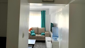 Een woonkamer met een bank, een bijzettafeltje en een waterdispenser.