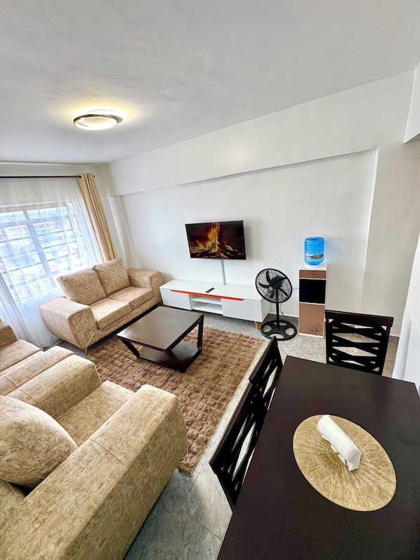 Un salon moderne comprenant un canapé, une table basse, un téléviseur et un coin repas avec des chaises et une table.