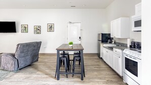 A modern kitchen with a dining area, white cabinets, a built-in oven, and a flat-screen TV. - Tropical Hideaway — Best Location- Walkable East Nashville (Nashville)