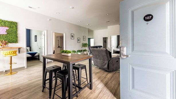 A modern interior with a dining area, a sofa, and a door marked with the number 107. - Tropical Hideaway — Best Location- Walkable East Nashville (Nashville)