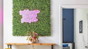 A room with a green wall, a neon sign, two yellow bar stools, and a bed with a blue blanket. - Tropical Hideaway — Best Location- Walkable East Nashville (Nashville)