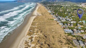 Vista aérea de un pueblo costero con playa, casas y una montaña al fondo.