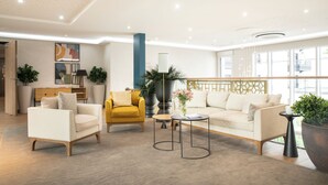 Un salon moderne comprenant un canapé, des fauteuils, une table basse et des plantes décoratives.