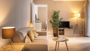 Un salon moderne avec un canapé, une table basse, une lampe, un téléviseur et une plante en pot.