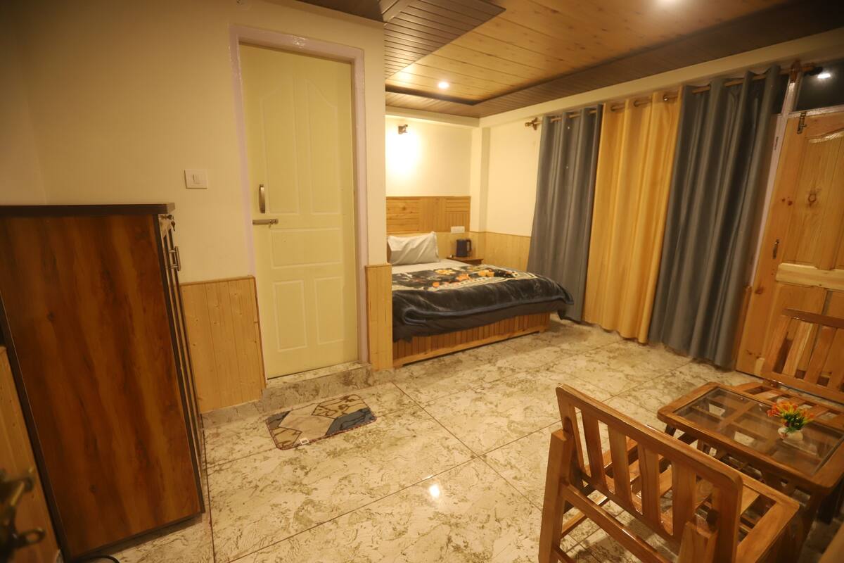 A compact bedroom with a bed, a small table, and a wooden wardrobe.
