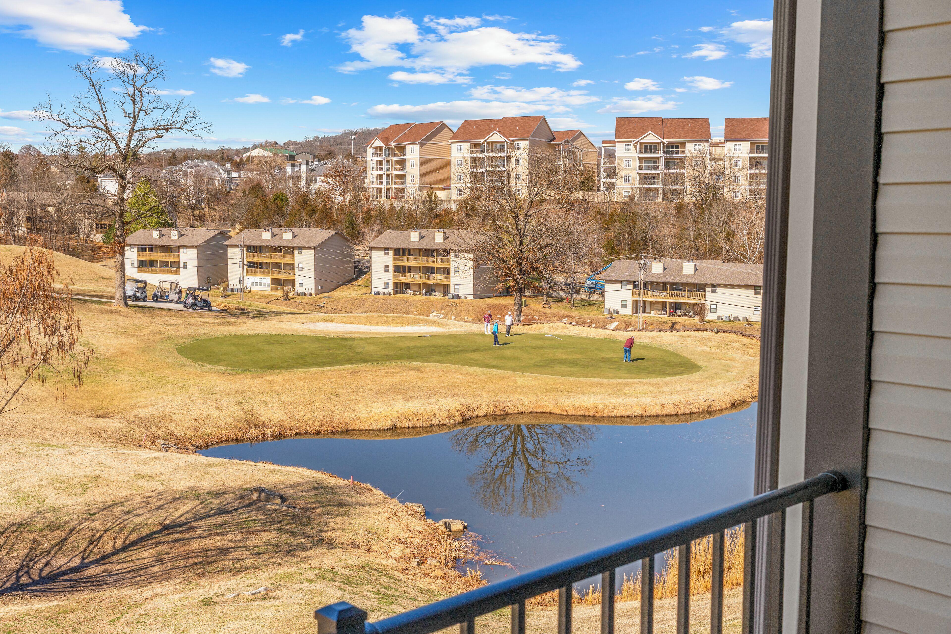 A view of a golf course with a pond, surrounded by apartment buildings.