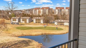 Une vue sur un terrain de golf avec un étang, entouré d’immeubles d’habitation.