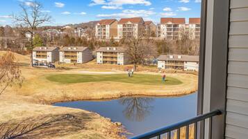 A view of a golf course with a pond, surrounded by apartment buildings.