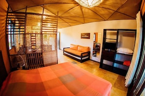 A room with a bed, a sofa, a wardrobe, and a window with a view. - Pousada Village Porto Mirim por Carpediem (Ceara-Mirim)