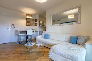 Ein modernes Wohnzimmer mit einem weißen Sofa, einem Glastisch und einem Essbereich mit einem weißen Stuhl und Tisch.
