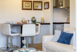 Eine moderne Küche mit Essbereich, ausgestattet mit einem Barhocker, einem weißen Sofa und gerahmten Bildern an der Wand.