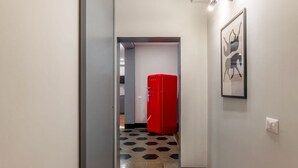 Ein Flur mit einem roten Kühlschrank, einem sechseckig gemusterten Boden und einem gerahmten Bild an der Wand.