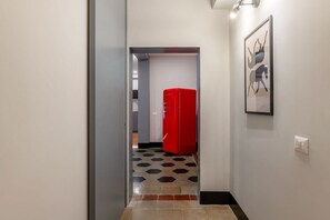 Ein Flur mit einem roten Kühlschrank, einem sechseckig gemusterten Boden und einem gerahmten Bild an der Wand.
