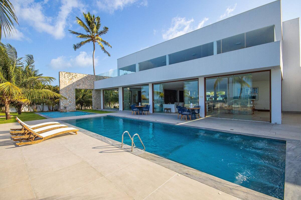 A modern house with a swimming pool, outdoor furniture, and palm trees.