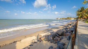 Une plage avec une clôture en bois, un ciel bleu clair et une mer calme.