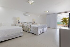 Une chambre d’hôtel avec deux lits, une grande fenêtre donnant sur l’océan et un balcon.