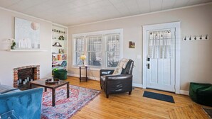 A living room with a fireplace, a leather armchair, a blue sofa, and a bookshelf. - Grandmas House Timeless Charm (Covington)