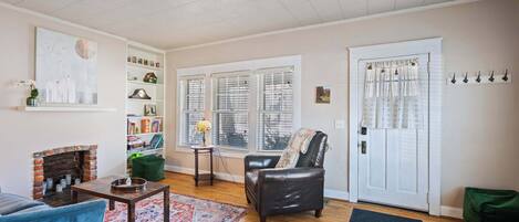 A living room with a fireplace, a leather armchair, a blue sofa, and a bookshelf.