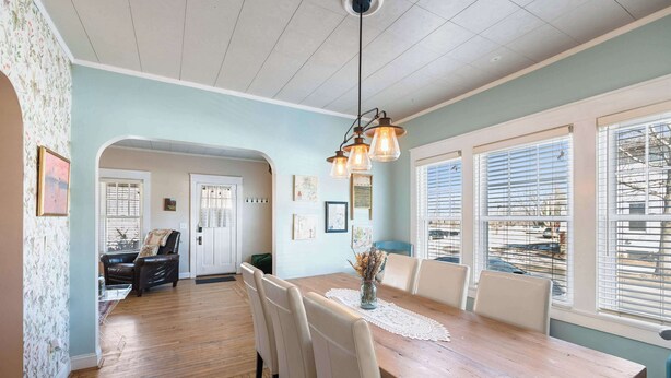 A dining area with a wooden table, white chairs, and a hanging light fixture. - Grandmas House Timeless Charm (Covington)