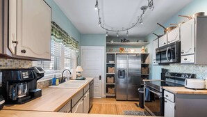 A modern kitchen with a stainless steel refrigerator, a microwave, and a coffee maker. - Grandmas House Timeless Charm (Covington)