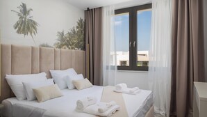 Een hotelkamer met een bed, een raam met gordijnen en uitzicht op palmbomen.